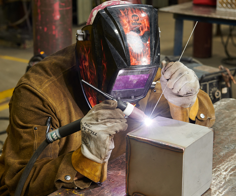 Student using an Arc torch, welding a piece of metal.