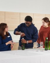 Three student standing at a serving table, making mocktails.