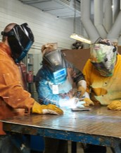 A group of students working on fabricating metal with a torch.