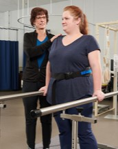 Instructor helping student learn about balancing poles for people learning to walk again.